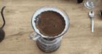 Image: V60 and glass carafe with filtered coffee on a table top next to pile of coffee beans