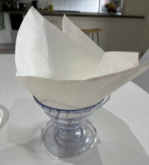 A paper napkin folded into a paper boat sitting on a table